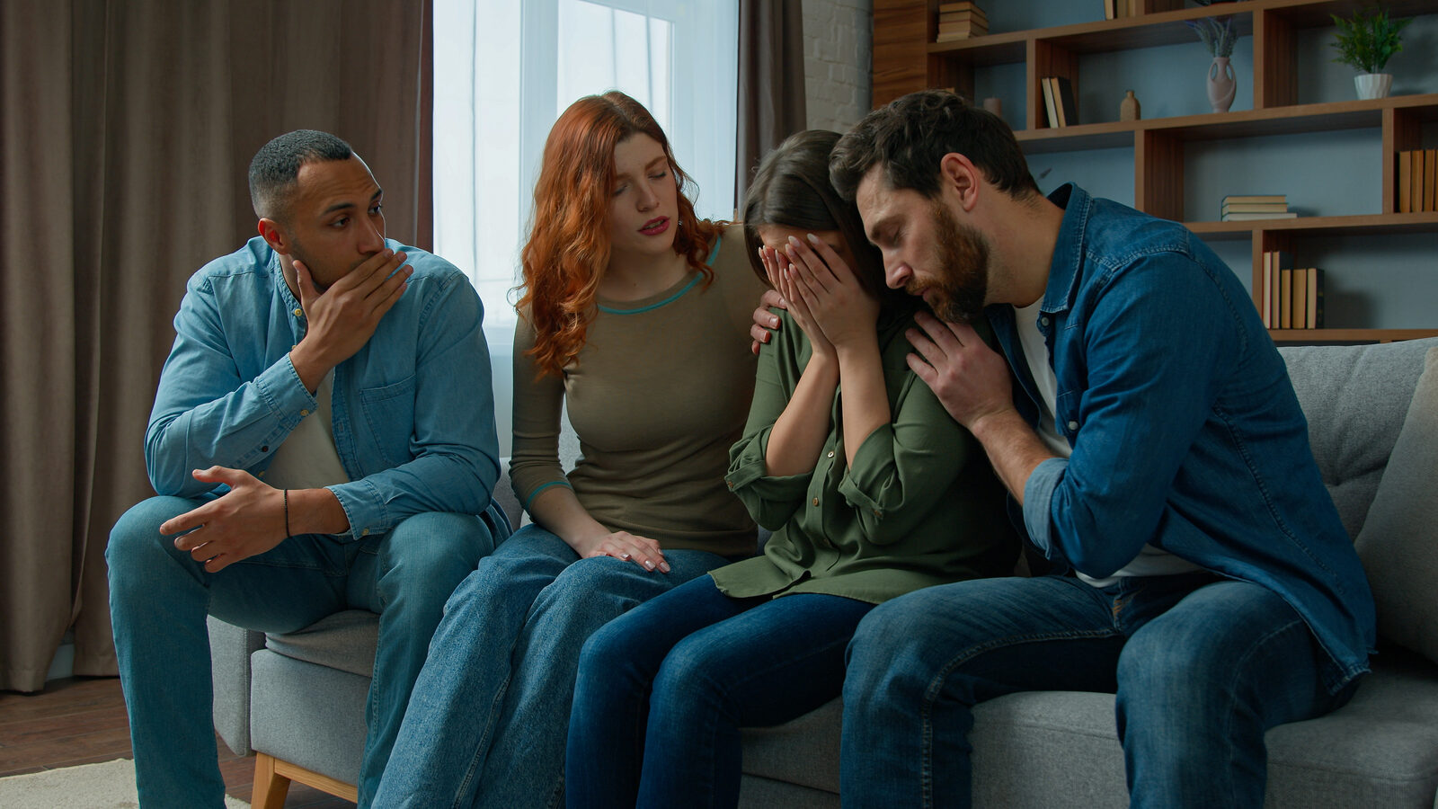 Friends comforting a grieving woman on a couch