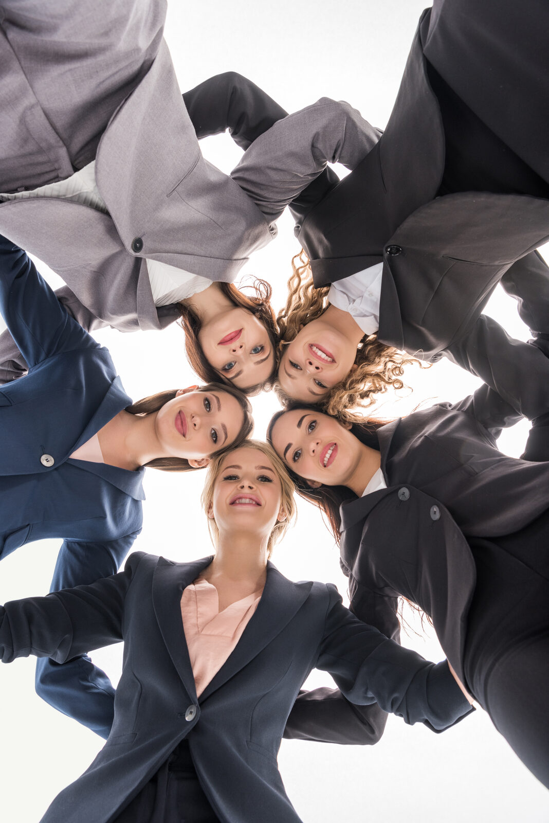 Group of women in a huddle looking down at the camera