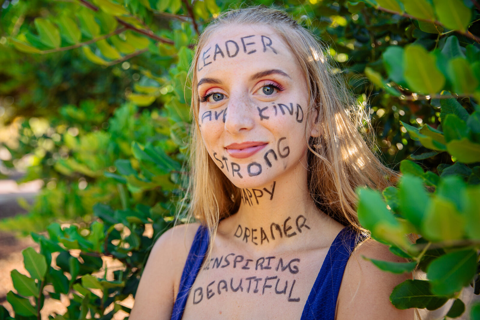 Woman with positive words written on her face and arms